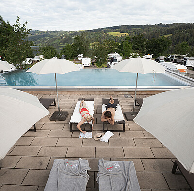 Paar liegt auf Poolliegen - Infinity Pool auf dem Campingplatz - Alpsee Camping Immenstadt
