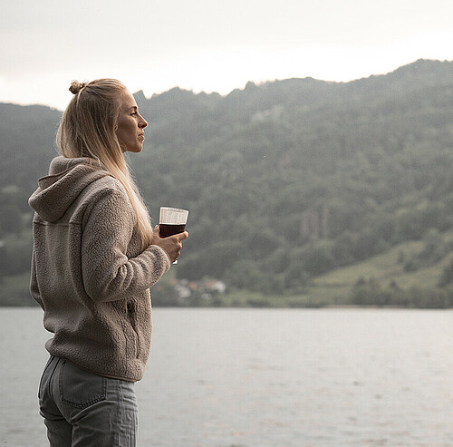 Frau steht auf Stein am Seeufer - Alpsee Camping Immenstadt