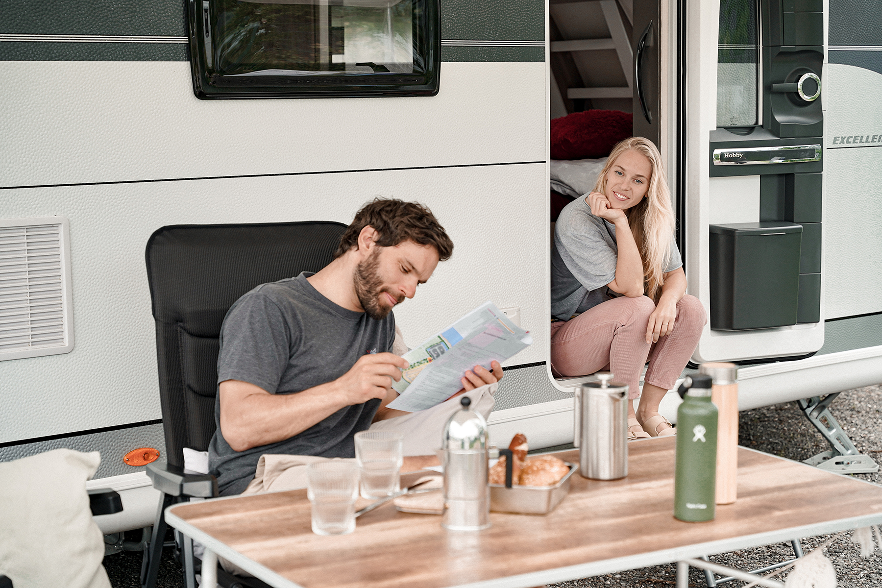 Mann plant Wanderung mit Wanderkarte im Campingurlaub und Frau sitzt daneben - Alpsee Camping Immenstadt